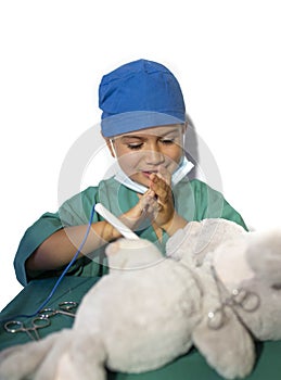 Happy child disguised as a surgeon playing doctor operating on a teddy bear