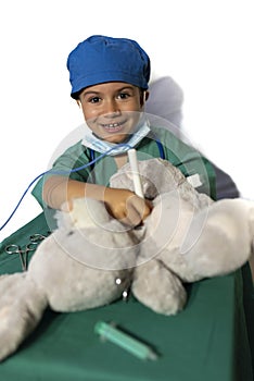 Happy child disguised as a surgeon playing doctor operating on a teddy bear