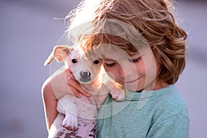 Happy child and dog hugs her with tenderness smiling. Little boy hugging puppies. Close up, copy space. Cute child boy