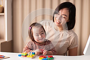 Happy child with down syndrome with mom rejoice at home, laugh