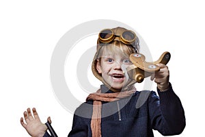Happy child dressed in pilot hat and glasses. Kid playing with wooden toy airplane. Dream and freedom concept. Retro