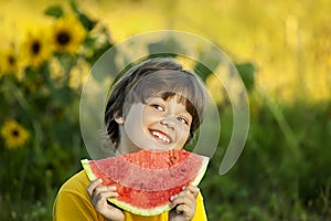 Happy child eating watermelon in garden. Boy with fruit outdoors