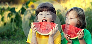 Happy child eating watermelon in garden. Two boys with fruit in