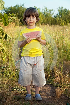 Happy child eating watermelon in garden. Two boys with fruit in