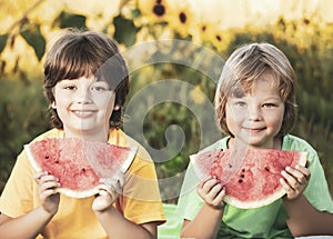 Happy child eating watermelon in garden. Two boys with fruit in park