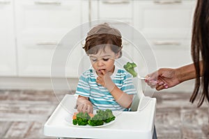 The happy child eats broccoli. Organic Cabbage and food on a plate.