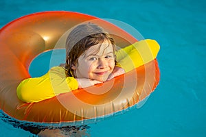 Happy child enjoying summer vacation outdoors in water in the swimming pool. Cute little kid in swimming suit relaxing