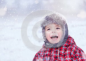 Happy child enjoying winter snowy day. Three years old cute smiling trendy hipster boy in winter wear. Kid playing outside. photo