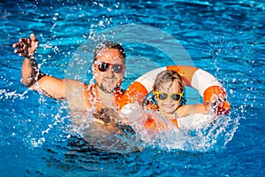 Happy child and father playing in swimming pool