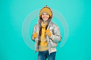 Happy child feel comfortable and warm in padded jacket and knitted clothing in winter weather, cold climate