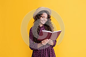 happy child with frizz hair read book on yellow background