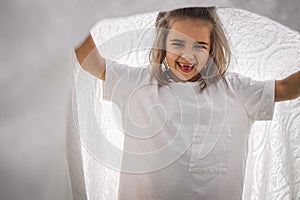 Happy child. Funny girl playing with a blanket. Smiling child girl. Cheerful child outdoors in nature