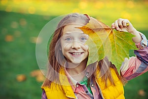 Happy child girl with autumn leaves outdoors. Cute little girl in autumn park. Little girl with autumn leaves in hand