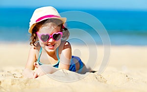 Happy child girl in bikini on beach in summer sea