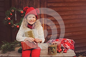 Happy child girl celebrating christmas outdoor at cozy wooden country house