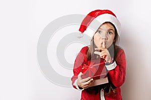 Happy child girl in Christmas hat holding red gift box isolated on white background