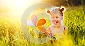 Happy child girl with colorful pinwheel windmill in summer