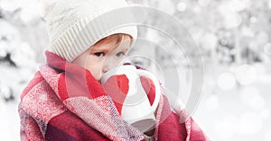 Happy child girl with cup of hot drink on cold winter outdoors