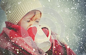 Happy child girl with cup of hot drink on cold winter outdoors