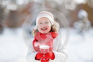 Happy child girl with a cup of hot tea in winter walk