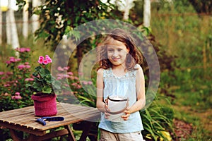 happy child girl decorating evening summer garden with candle holder