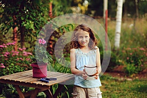 happy child girl decorating evening summer garden with candle holder