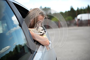 Happy child girl and dog chihuahua looking out the open car window