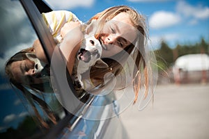 Happy child girl and dog chihuahua looking out the open car window