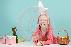 Happy child girl in Easter bunny rabbit ears and a basket of Easters eggs.