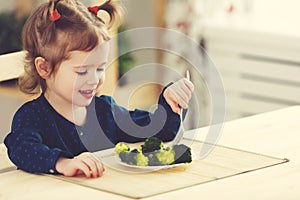 Happy child girl eating vegetables and laughs photo