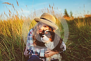 Happy child girl enjoying summer vacations with her dog, walking and playing on sunny meadow