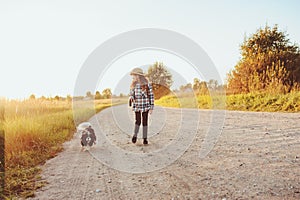 Happy child girl enjoying summer vacations with her dog, walking and playing on sunny meadow