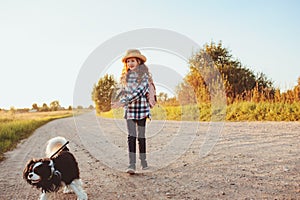 Happy child girl enjoying summer vacations with her dog, walking and playing on sunny meadow