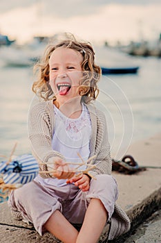 Happy child girl fooling and playing with toy bird on summer seacost photo