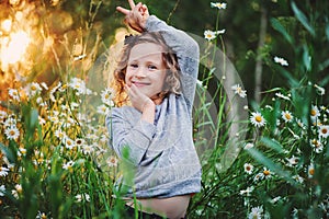 Happy child girl fooling on summer field with flowers photo