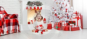 Happy child girl with gift in morning at Christmas tree