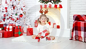 Happy child girl with gift in morning at Christmas tree