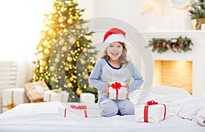 Happy child girl with gifts in bed on Christmas morning