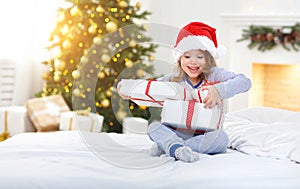 Happy child girl with gifts in bed on Christmas morning