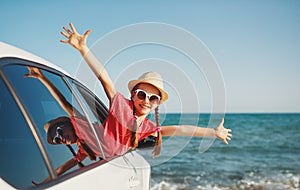 Happy child girl goes to summer travel trip in car