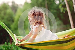 Happy child girl having fun and relaxing in hammock in summer