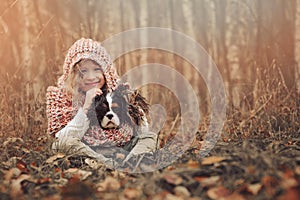 Happy child girl with her spaniel dog on cozy warm autumn walk