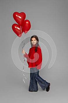 happy child girl holding red heart shaped balloon