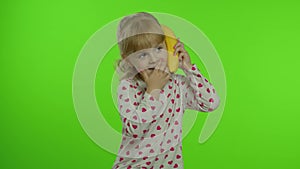 Happy child girl kid imitating telephone conversation with banana isolated on chroma key background
