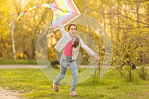happy child girl with a kite running on meadow in nature.