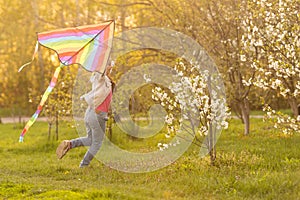 happy child girl with a kite running on meadow in nature.