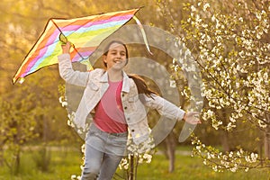 happy child girl with a kite running on meadow in nature.