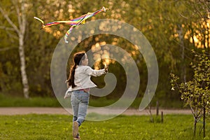 happy child girl with a kite running on meadow in nature.