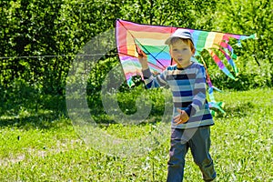 Happy child girl with a kite running on meadow in summer in nature