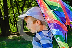 Happy child girl with a kite running on meadow in summer in nature